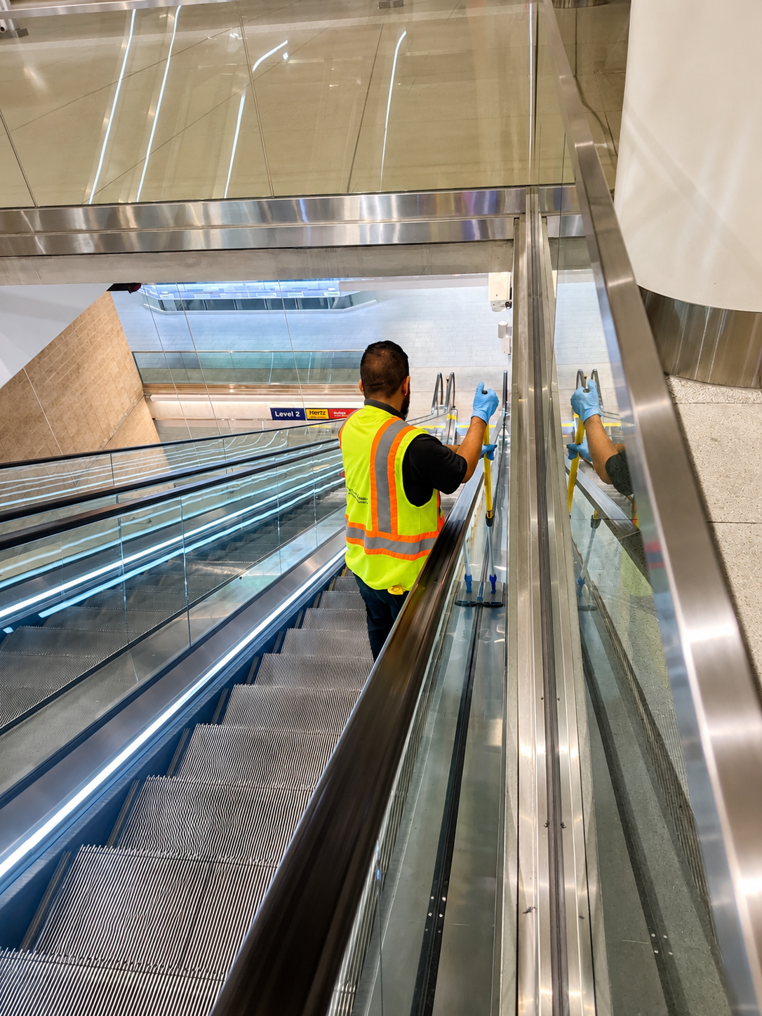 Gloss-N-Gleams staff member cleaning an airport escalator handrail